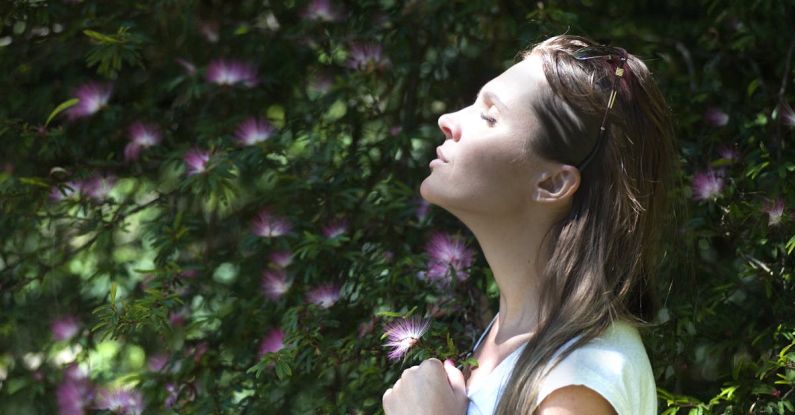Meditation Calm - Woman Closing Her Eyes Against Sun Light Standing Near Purple Petaled Flower Plant