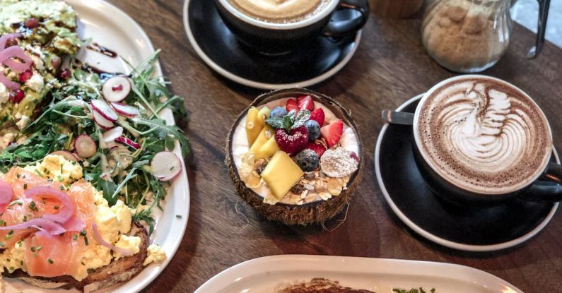 Smoothie Recipes - Appetizing dishes and smoothie bowl placed on table with cups of coffee in modern cafe