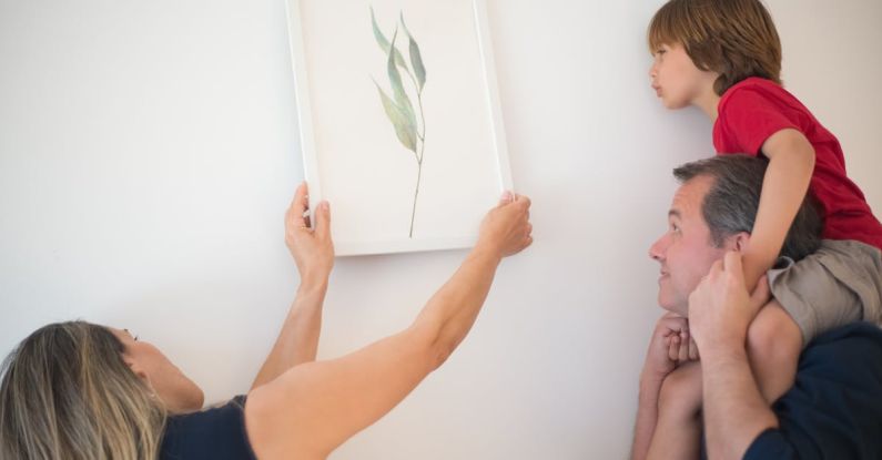 New Parents - Woman Putting Wall Art on the Wall