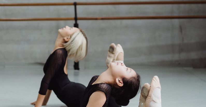 Yoga Beginners - Flexible Asian ballerinas stretching on floor in dance class