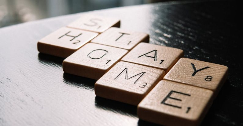 Save For House - High angle of scrabble letter tiles arranged on black wooden table in inscription Stay Home in living room