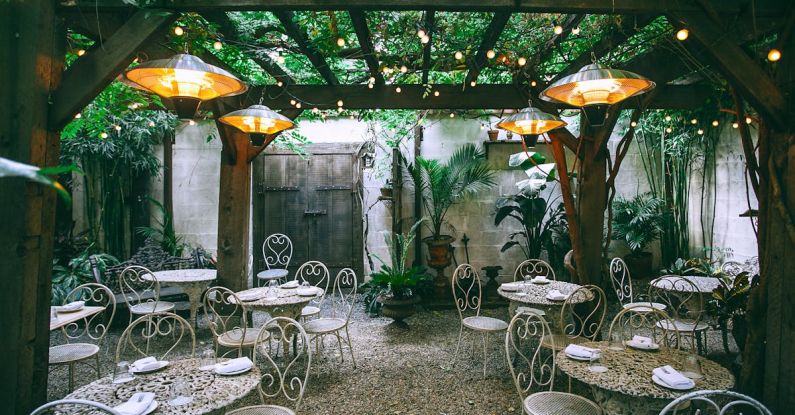 Setting Boundaries - Cafe with setting on ornamental tables near chairs under decorative lamps in backyard on summer day